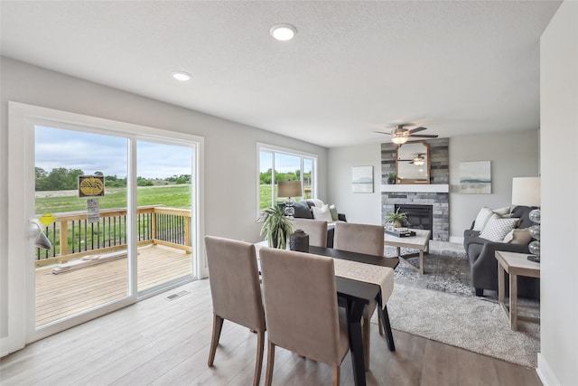 3251 NW Brookside Dr, Grimes, IA 50111 - dining space with light wood-style floors, a stone fireplace, a ceiling fan, and recessed lighting