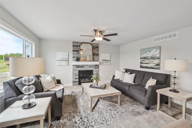 3251 NW Brookside Dr, Grimes, IA 50111 - living room featuring ceiling fan, wood finished floors, a stone fireplace, and baseboards