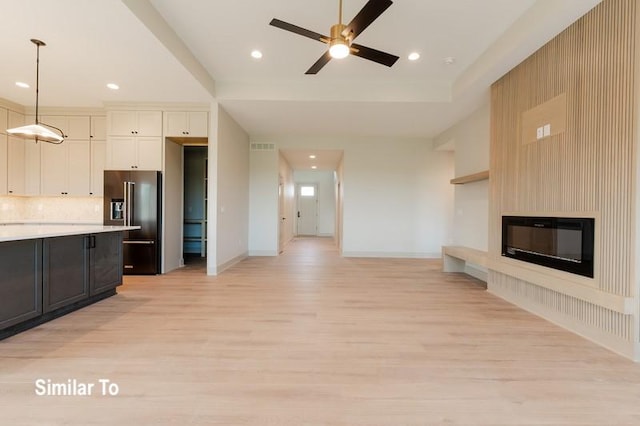 unfurnished living room with ceiling fan, light wood-type flooring, and a fireplace