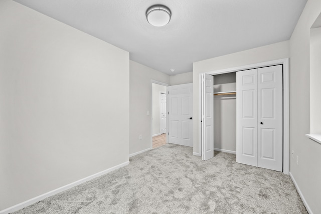 unfurnished bedroom featuring light carpet and a closet