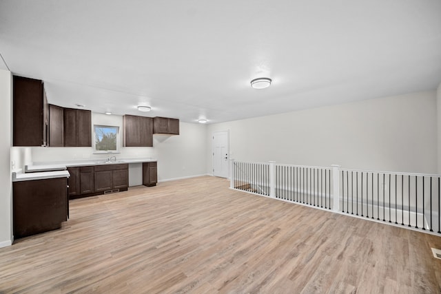 kitchen featuring dark brown cabinetry, sink, and light hardwood / wood-style flooring