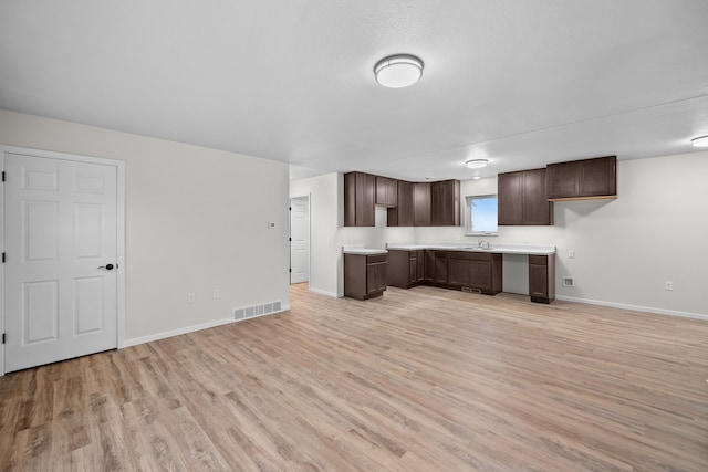 kitchen featuring dark brown cabinets, light wood-type flooring, and sink