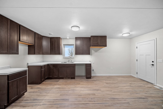 kitchen featuring dark brown cabinetry, sink, and light hardwood / wood-style floors