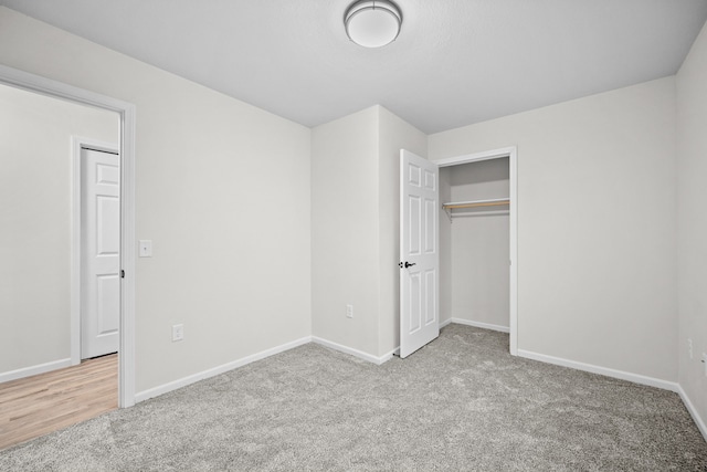 unfurnished bedroom with light colored carpet and a closet