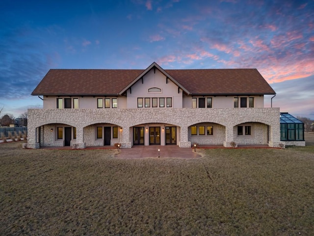 7217 NW 107th St, Johnston, IA 50131 - view of front of property with stucco siding, stone siding, a patio area, and a front lawn