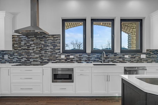 kitchen featuring sink, stainless steel appliances, light stone countertops, white cabinets, and wall chimney exhaust hood