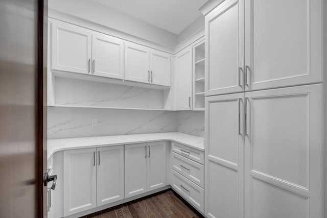 kitchen with stainless steel refrigerator, dark hardwood / wood-style floors, light stone counters, white cabinets, and decorative backsplash