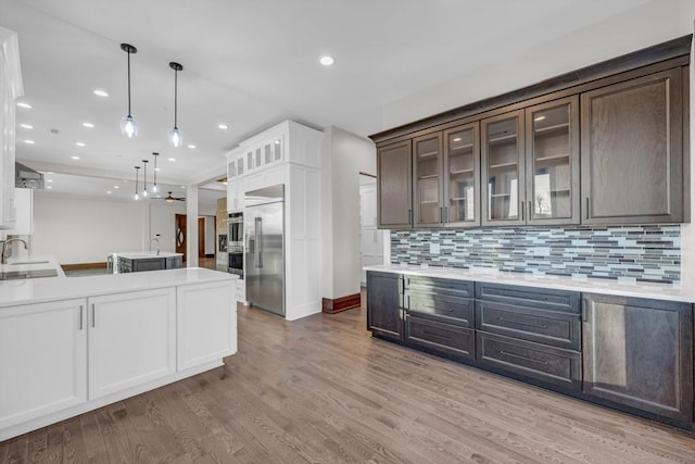 kitchen featuring sink, hanging light fixtures, backsplash, stainless steel built in refrigerator, and dark brown cabinetry