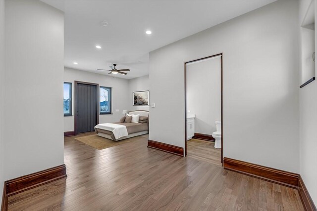 bedroom with ensuite bath, light hardwood / wood-style flooring, and ceiling fan