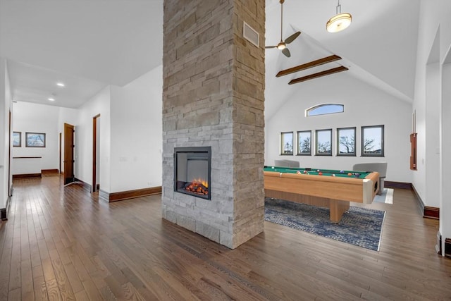 rec room with a stone fireplace, high vaulted ceiling, beamed ceiling, dark hardwood / wood-style flooring, and pool table