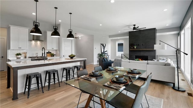 dining area featuring ceiling fan, a fireplace, and light hardwood / wood-style flooring