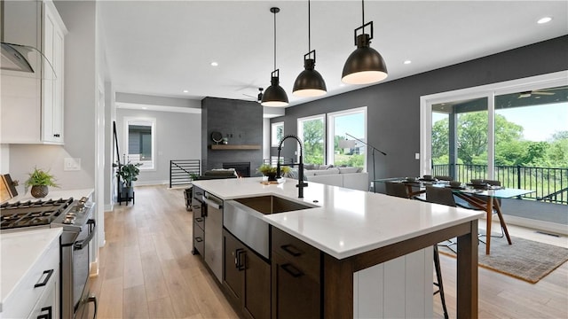 kitchen with a kitchen island with sink, white cabinetry, sink, and stainless steel appliances