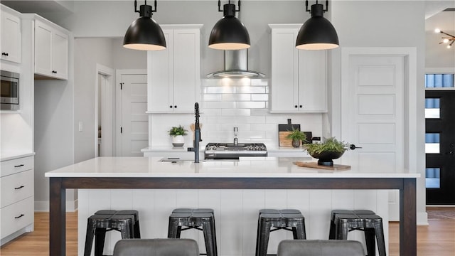 kitchen with pendant lighting, a center island with sink, and white cabinetry