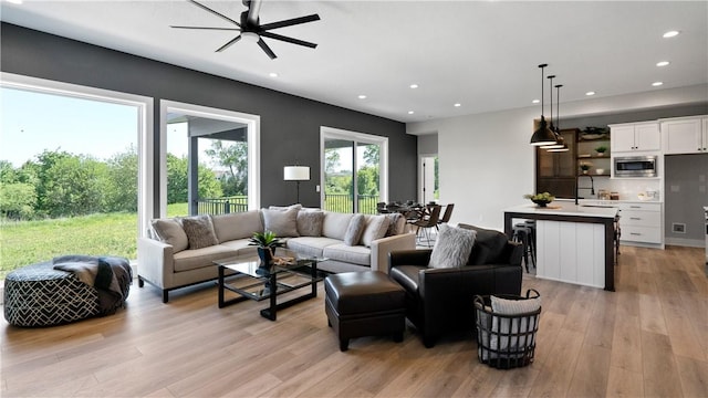 living room featuring ceiling fan, light hardwood / wood-style flooring, and sink