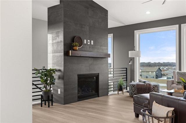 living room featuring a tile fireplace, vaulted ceiling, and light wood-type flooring