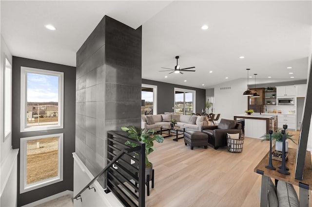 living room featuring ceiling fan, sink, light hardwood / wood-style floors, and lofted ceiling