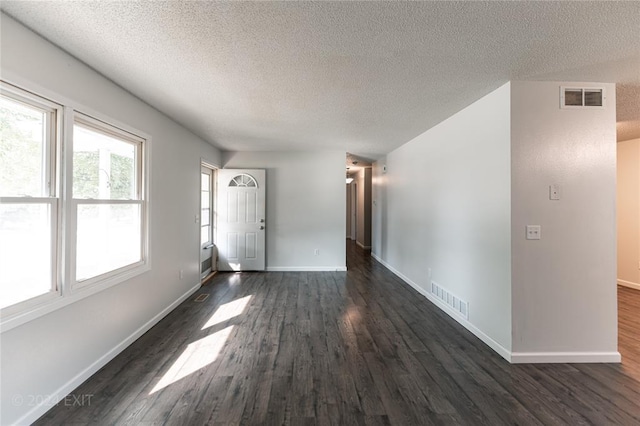 empty room featuring a textured ceiling and dark hardwood / wood-style floors