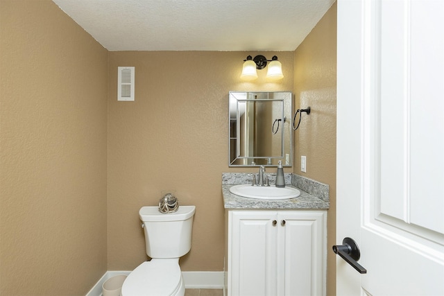 bathroom with vanity, a textured ceiling, and toilet