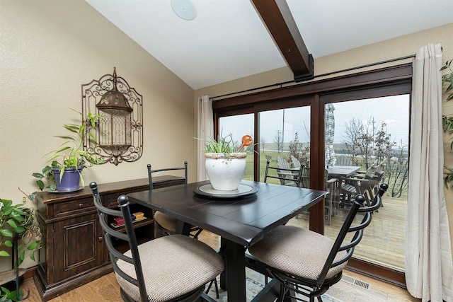 dining area with vaulted ceiling with beams and light wood-type flooring