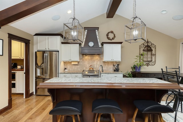 kitchen featuring white cabinetry, hanging light fixtures, stainless steel appliances, backsplash, and custom range hood