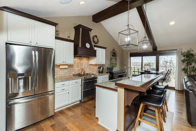 kitchen with white cabinets, stainless steel appliances, a kitchen island with sink, and sink