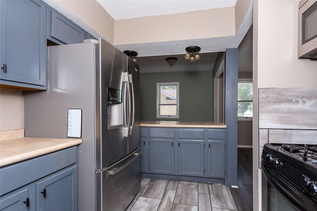 kitchen featuring stainless steel appliances, blue cabinets, and a textured ceiling