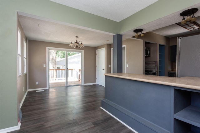 kitchen featuring an inviting chandelier, dark wood-type flooring, hanging light fixtures, and a textured ceiling