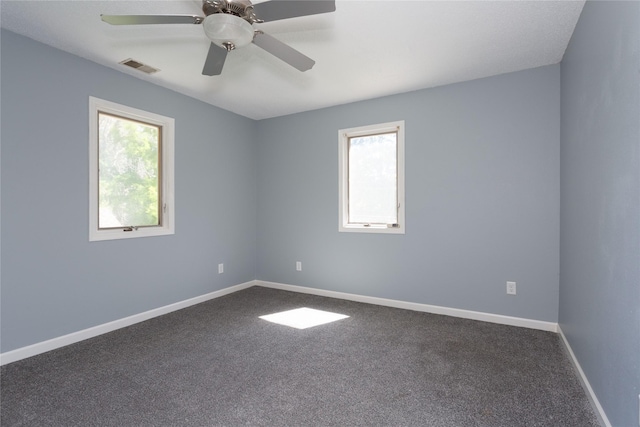 carpeted spare room featuring a wealth of natural light and ceiling fan