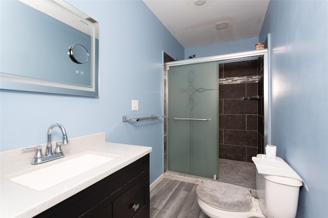 bathroom with hardwood / wood-style flooring, vanity, toilet, and walk in shower