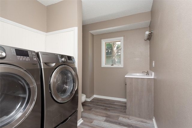 clothes washing area featuring sink, independent washer and dryer, and light wood-type flooring