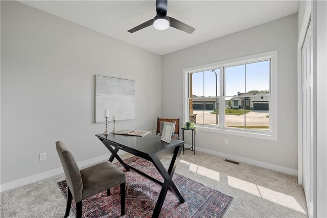 carpeted home office featuring ceiling fan