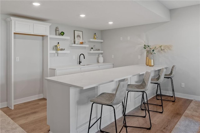 kitchen with a breakfast bar, open shelves, light wood-style floors, a peninsula, and white cabinets