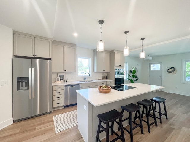 kitchen with a breakfast bar, a center island, sink, and appliances with stainless steel finishes