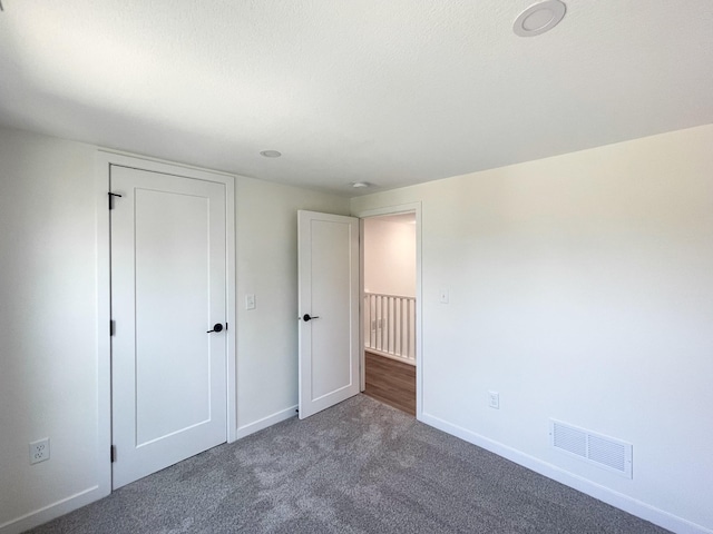 unfurnished bedroom with dark carpet