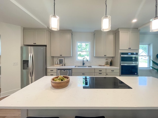 kitchen with appliances with stainless steel finishes, backsplash, sink, pendant lighting, and gray cabinets