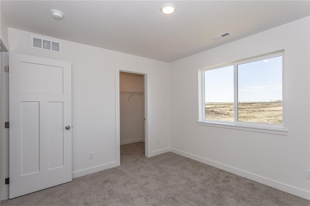 unfurnished bedroom featuring light colored carpet, a spacious closet, and a closet