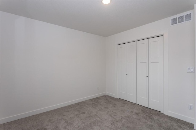 unfurnished bedroom with light colored carpet and a closet