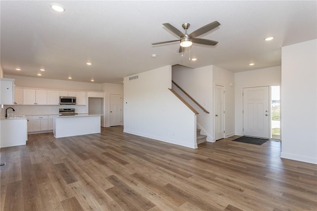 unfurnished living room featuring hardwood / wood-style flooring, ceiling fan, and sink