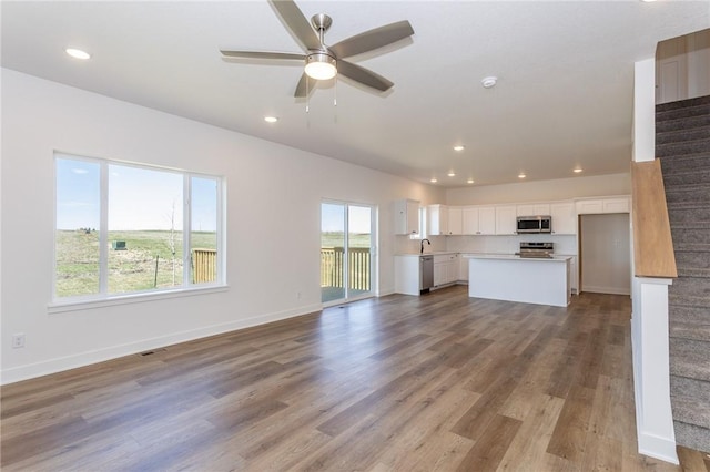 unfurnished living room featuring ceiling fan, sink, and light hardwood / wood-style floors