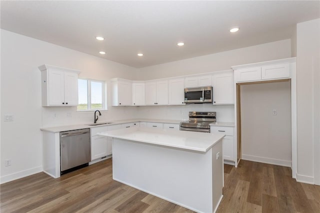 kitchen with stainless steel appliances, sink, hardwood / wood-style flooring, a center island, and white cabinetry