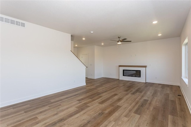 unfurnished living room featuring ceiling fan and hardwood / wood-style flooring