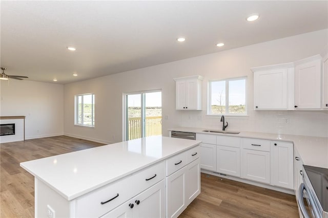 kitchen with ceiling fan, sink, a kitchen island, light hardwood / wood-style floors, and white cabinets