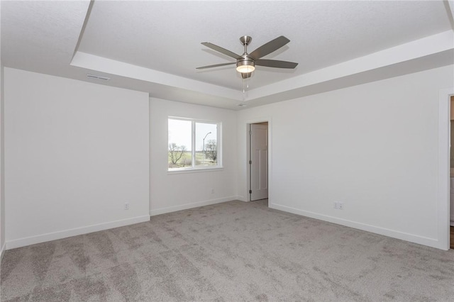 carpeted spare room featuring ceiling fan and a tray ceiling