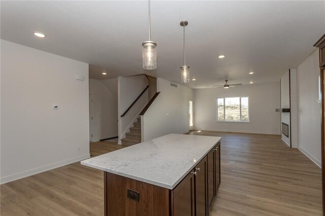 kitchen with ceiling fan, a center island, light hardwood / wood-style floors, and decorative light fixtures