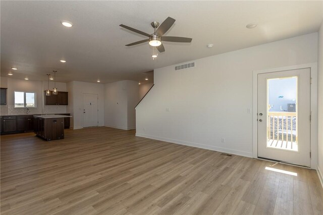 unfurnished living room featuring hardwood / wood-style flooring, ceiling fan with notable chandelier, and sink