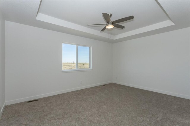 carpeted spare room with ceiling fan and a tray ceiling