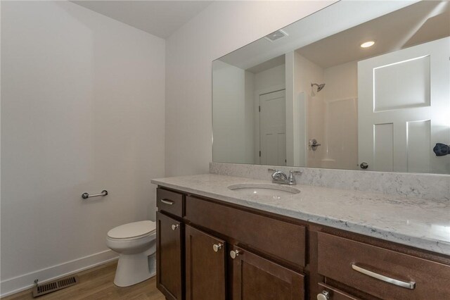 bathroom with toilet, vanity, wood-type flooring, and walk in shower