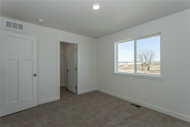 unfurnished bedroom with a spacious closet, a closet, and carpet