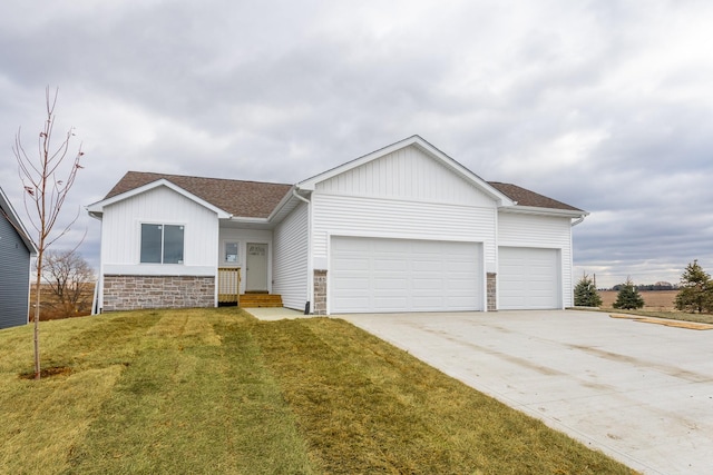 985 11th St, Waukee, IA 50263 - view of front of house with a front lawn, stone siding, a garage, and driveway