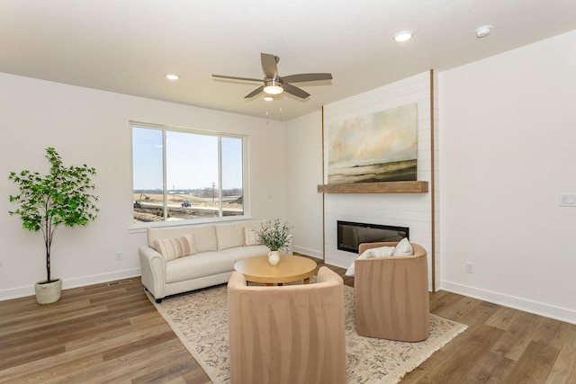 985 11th St, Waukee, IA 50263 - living area with a fireplace, baseboards, a ceiling fan, and wood finished floors